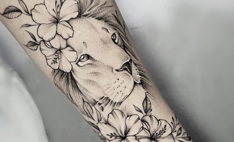 Tatuagem de leão com flores harmoniza força e feminilidade